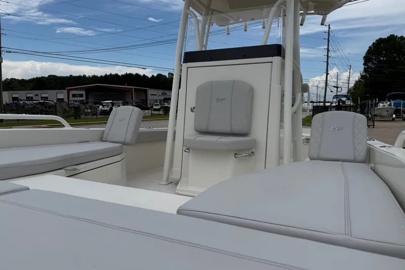 Slide: The Image of 2024 Ranger 2360 Bay boat interior with cushioned seating and console, under a partly cloudy sky. - 23