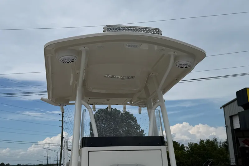 Slide: The Image of 2024 Ranger 2360 Bay boat T-top with speakers and LED lights under a cloudy sky. - 39