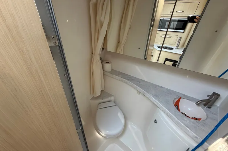 Slide: The Image of 2023 Regal 28 Express boat bathroom with sink, toilet, and mirror. - 26