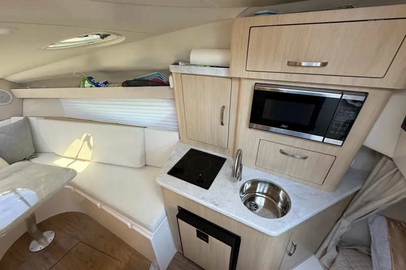 Slide: The Image of 2023 Regal 28 Express boat interior with kitchenette, microwave, sink, and seating area. - 22