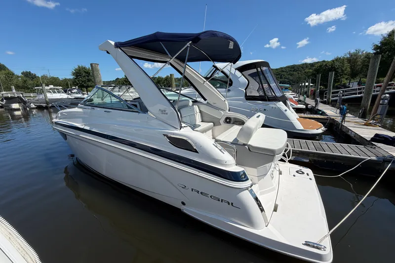 Slide: The Image of 2023 Regal 28 Express boat docked at marina under clear blue sky. - 2