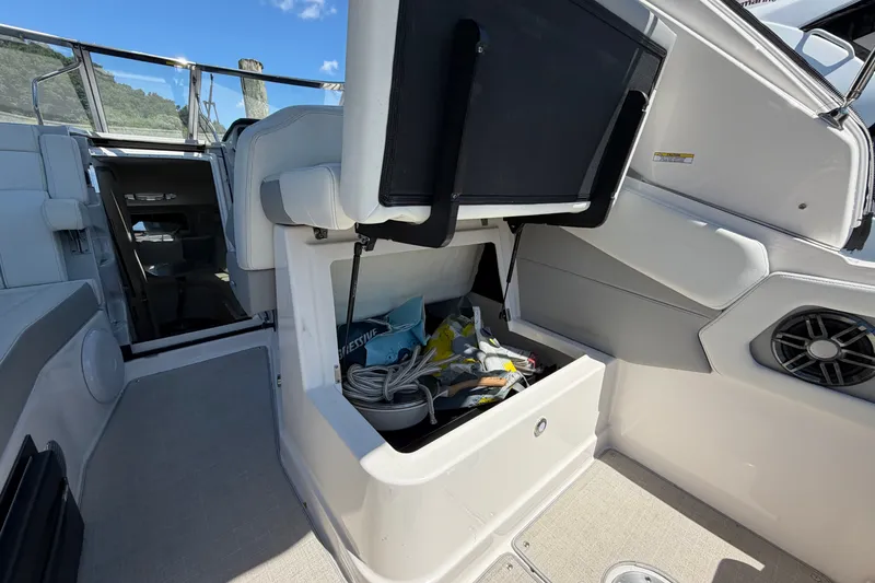 Slide: The Image of 2023 Regal 28 Express boat interior storage compartment with open seat and visible accessories. - 15