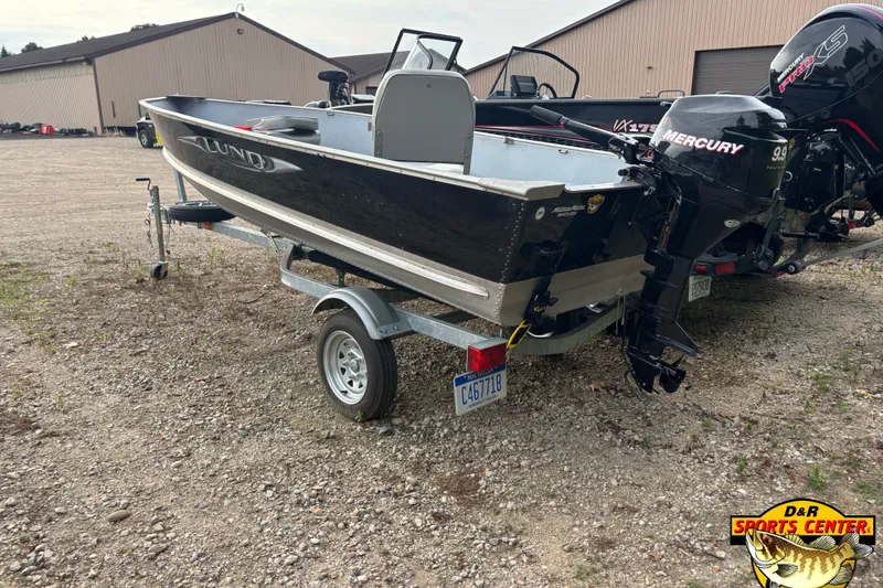 Slide: The Image of 2011 Lund WD 14 boat on trailer with Mercury outboard motor, parked outdoors. - 1