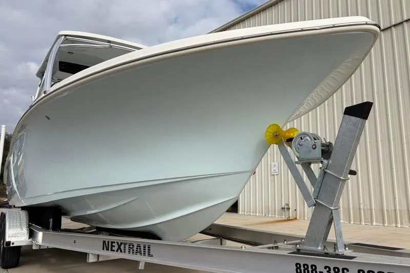 Slide: The Image of 2024 Key West 239 DFS boat on trailer, parked near a metal building. - 9