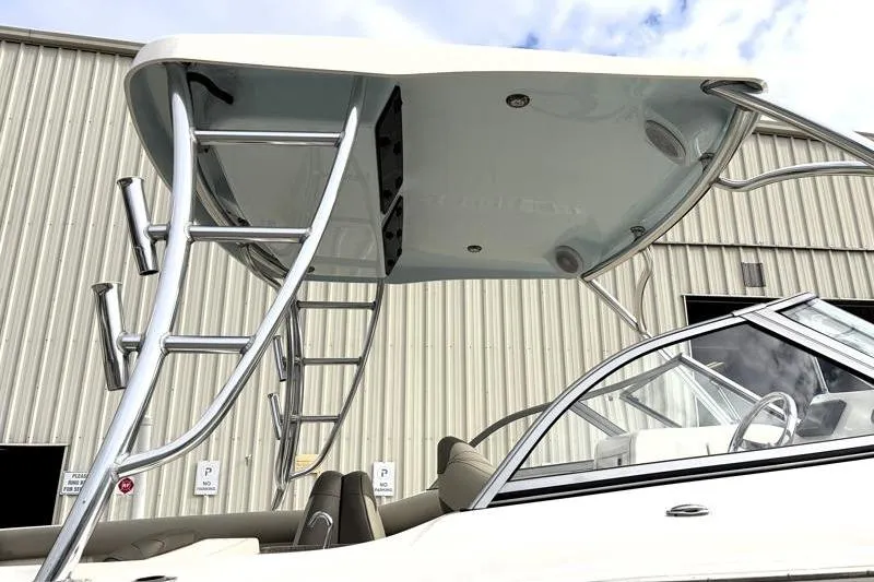 Slide: The Image of 2024 Key West 239 DFS boat with sleek T-top and ladder, parked near a warehouse. - 13