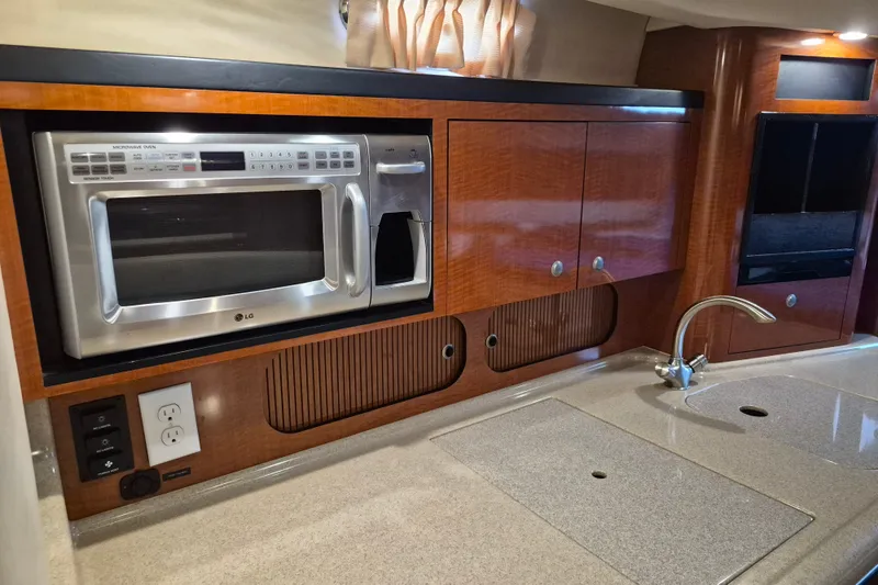 Slide: The Image of 2005 Sea Ray 340 Sundancer galley with microwave, sink, and wooden cabinetry. - 15