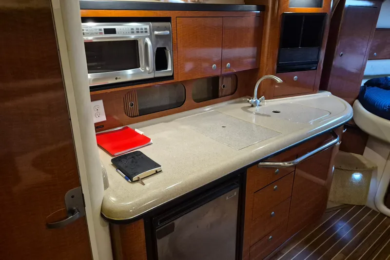 Slide: The Image of 2005 Sea Ray 340 Sundancer galley with microwave, sink, and wooden cabinetry. - 16
