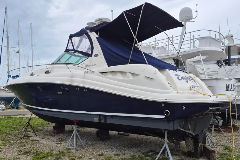 Slide: The Image of 2005 Sea Ray 340 Sundancer boat on stands, with blue and white exterior, in a marina. - 2