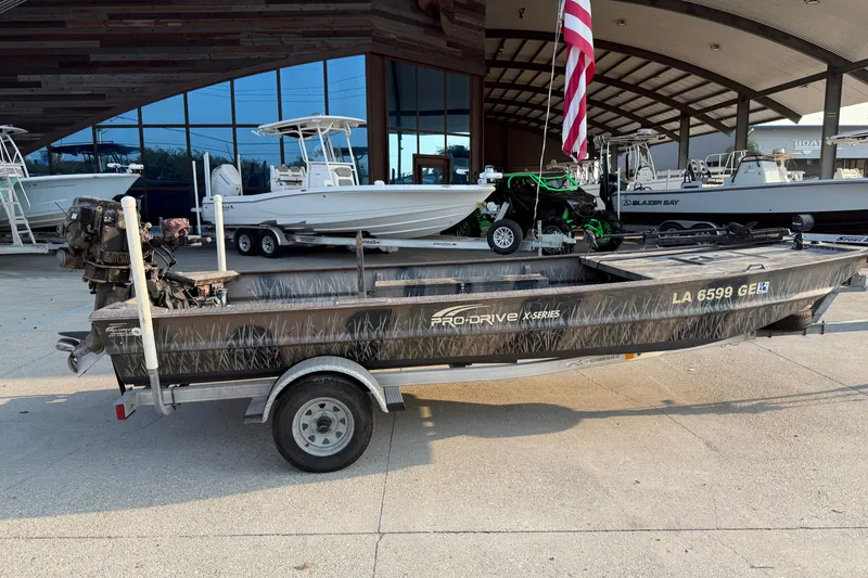 Slide: The Image of 2015 Custom Pro Drive 1754 boat on trailer, parked outside a showroom with other boats. - 2