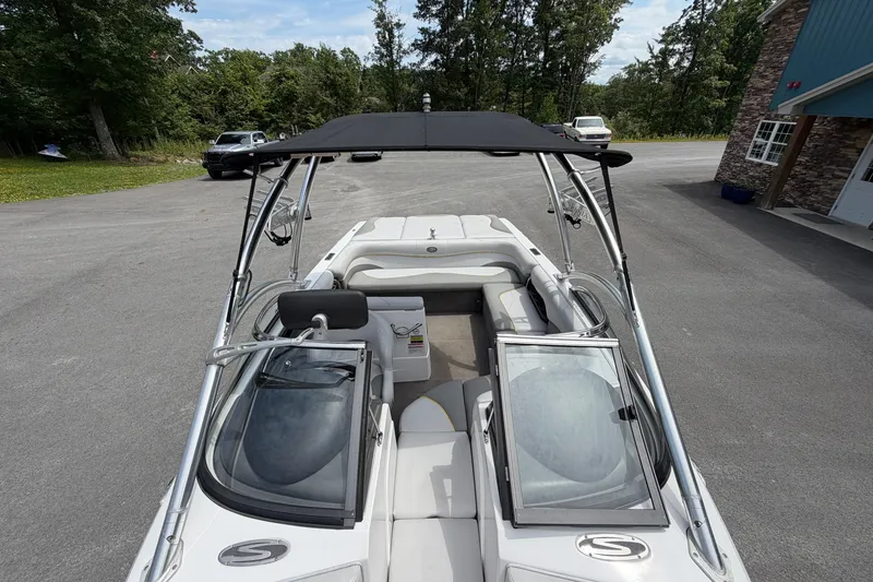 Slide: The Image of 2008 Supra Launch 22 SSV boat with open bow seating and canopy, parked outdoors. - 14