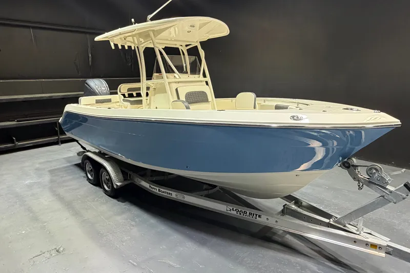 The Image of 2023 Cobia 237 Center Console boat on trailer in showroom setting. - 1