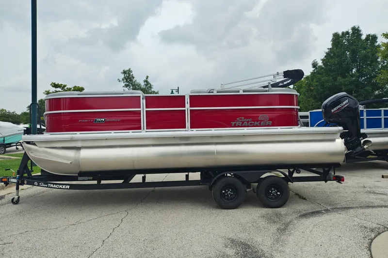 The Image of 2026 Sun Tracker Party Barge 20 DLX pontoon boat on trailer, red and silver design. - 1