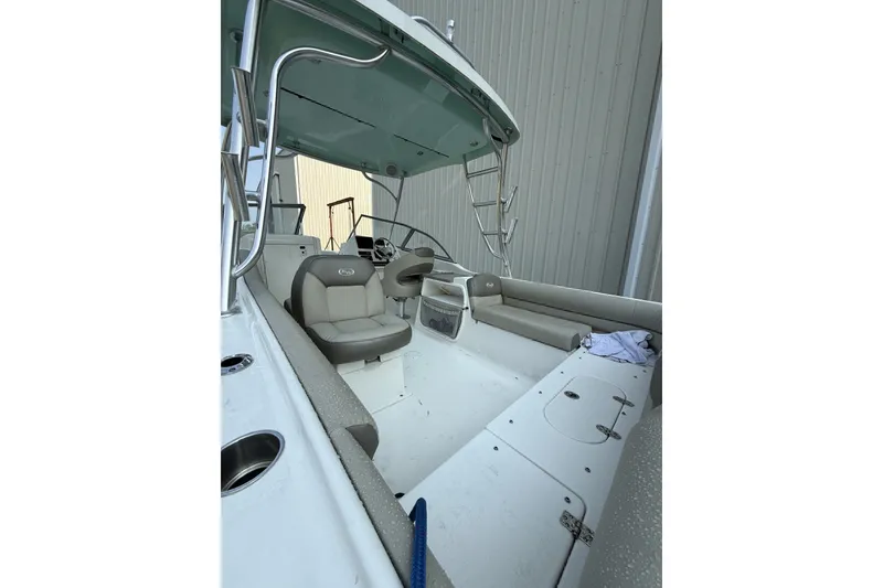 Slide: The Image of 2023 Key West 239 DFS boat interior with seating and helm, docked near a building. - 4