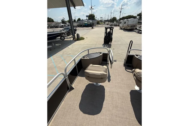 Slide: The Image of 2022 Sun Tracker Bass Buggy 18 DLX pontoon boat interior with seating, parked outdoors. - 14