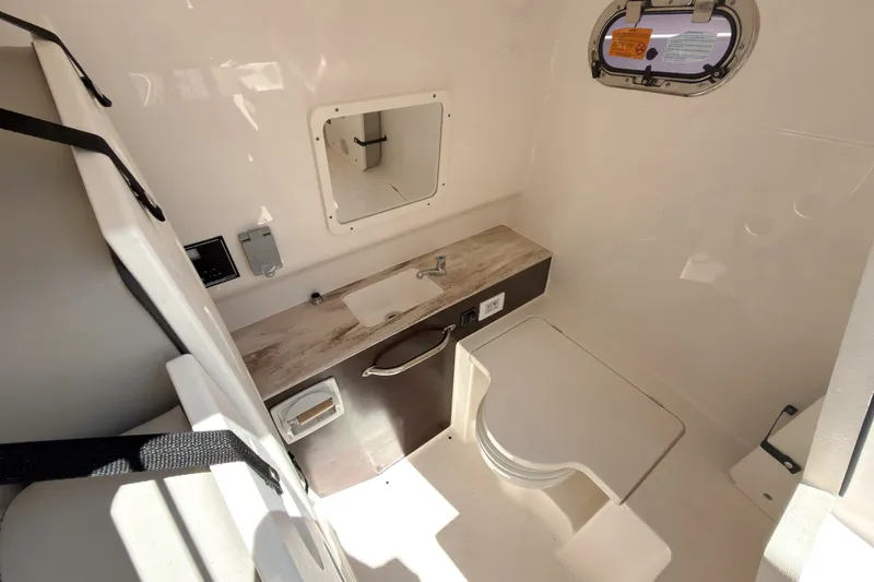 Slide: The Image of 2022 Pursuit S 288 Sport boat interior with sink, toilet, and window. - 21