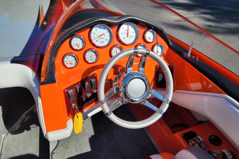 Slide: The Image of Interior of a 2015 Cobra 260 Venom boat with vibrant orange dashboard and gauges. - 10