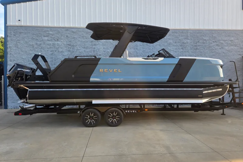 The Image of 2027 Revel RS25L boat on trailer, sleek design, parked outside industrial building. - 1