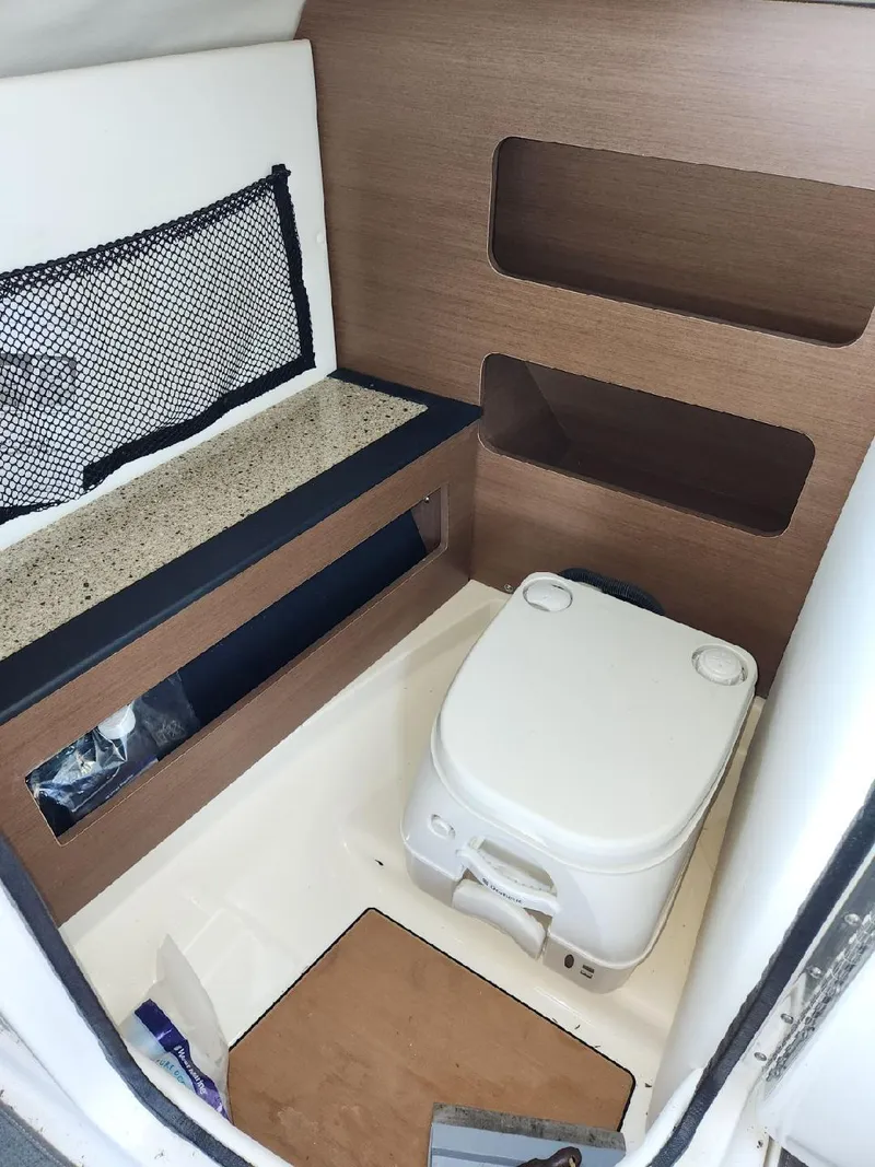 Slide: The Image of Interior of a 2015 Sea Ray 220 Sundeck featuring a toilet and storage space. - 30