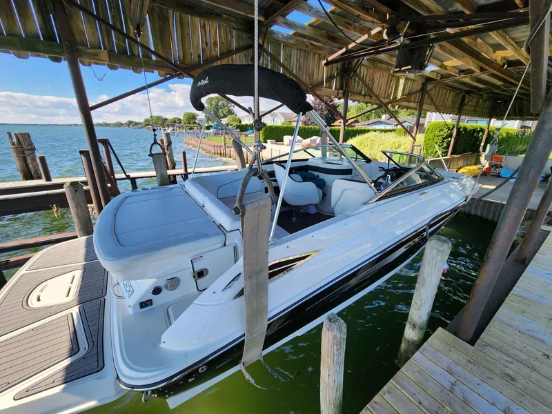Slide: The Image of A 2015 Sea Ray 220 Sundeck is docked in a covered boathouse by the water. - 22
