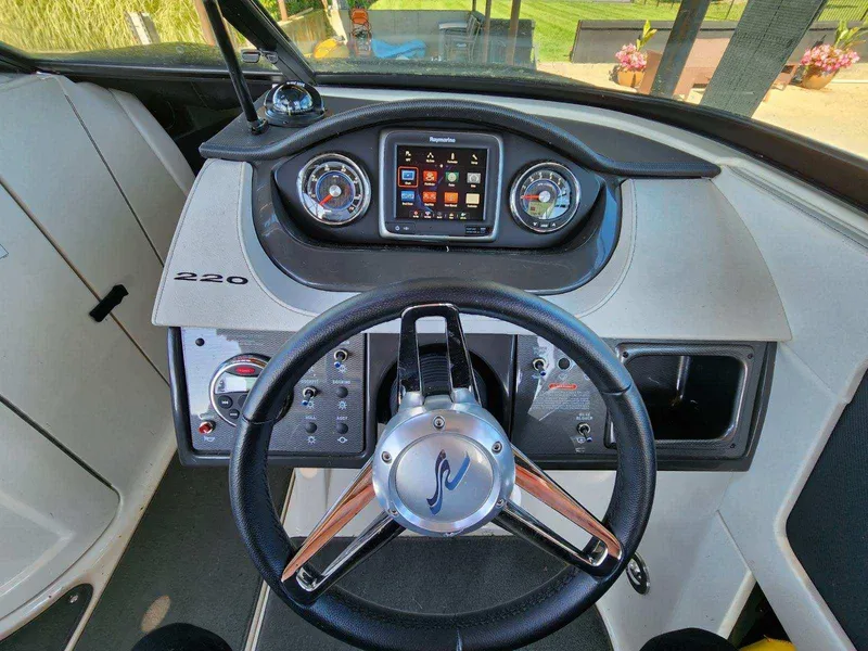 Slide: The Image of The image shows the helm of a 2015 Sea Ray 220 Sundeck boat. - 26