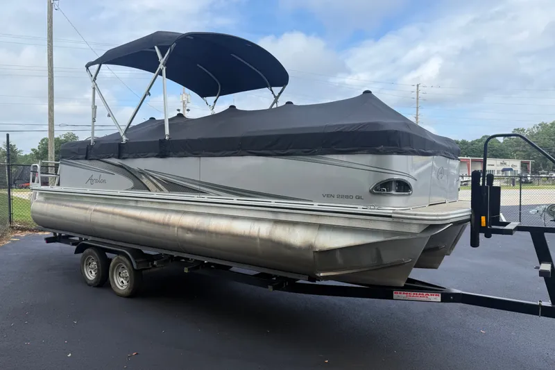 Slide: The Image of 2021 Avalon 2280 Venture Quad Lounger pontoon boat on trailer, covered and parked outdoors. - 8