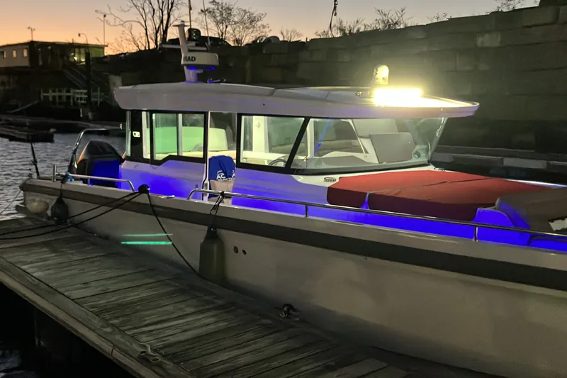 Slide: The Image of 2022 Axopar 37 XC Cross Cabin boat docked at sunset with illuminated interior. - 33