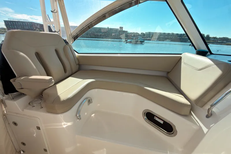 Slide: The Image of 2015 Pursuit DC 325 Dual Console interior with beige seating and waterfront view. - 8