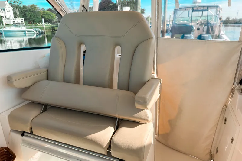 Slide: The Image of Captain's chair on 2015 Pursuit DC 325 Dual Console boat, docked with scenic marina view. - 7