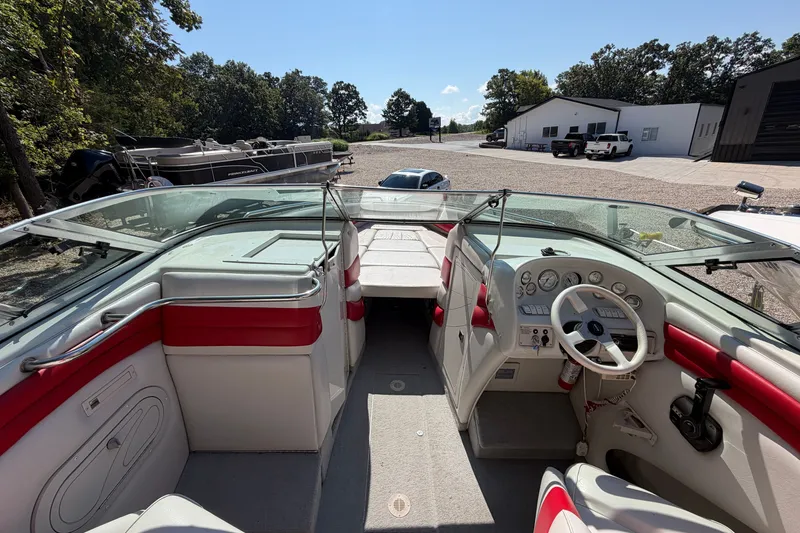 Slide: The Image of 2006 Crownline 266 BR boat interior with red and white seating, parked outdoors. - 10