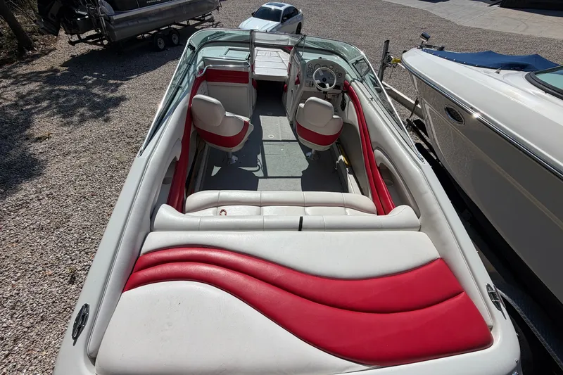 Slide: The Image of 2006 Crownline 266 BR boat interior with red and white seating, parked on gravel. - 6