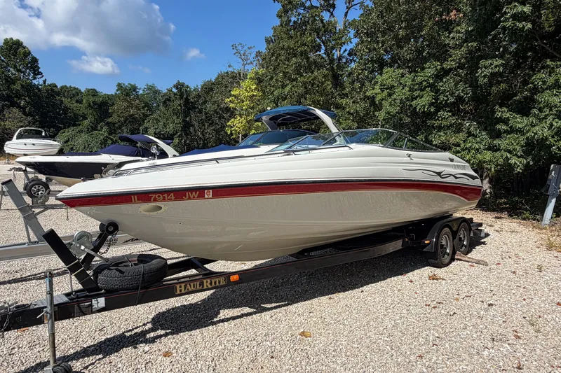 Slide: The Image of 2006 Crownline 266 BR boat on trailer, parked outdoors with trees in background. - 2