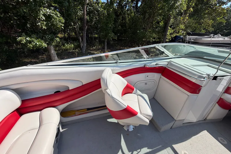 Slide: The Image of 2006 Crownline 266 BR boat interior with red and white seating, near wooded area. - 9
