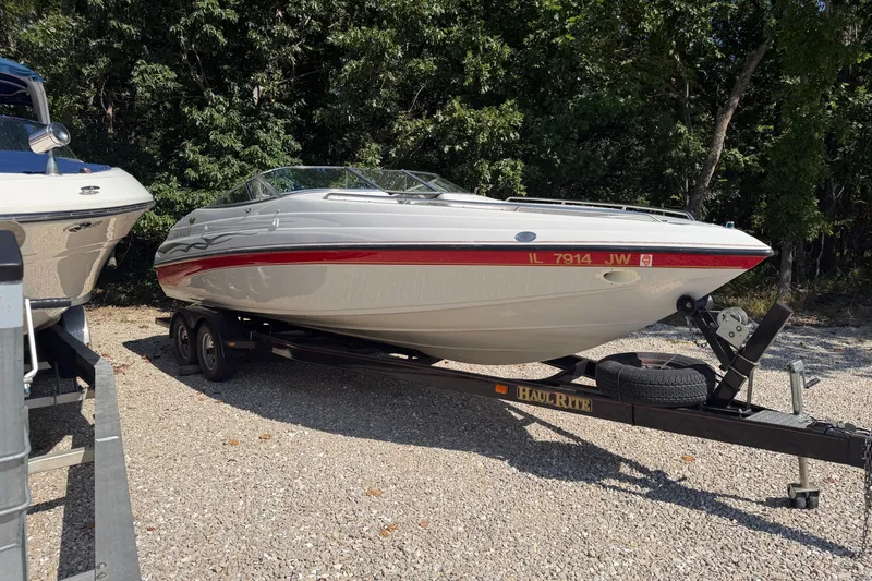 The Image of 2006 Crownline 266 BR boat on trailer, parked outdoors with trees in background. - 1