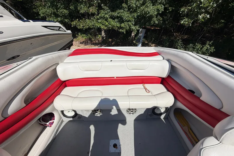 Slide: The Image of 2006 Crownline 266 BR boat interior with red and white seating, surrounded by trees. - 7