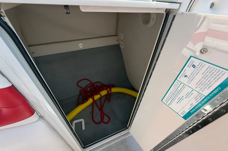 Slide: The Image of Storage compartment in a 2006 Crownline 266 BR boat with red rope and yellow hose. - 12