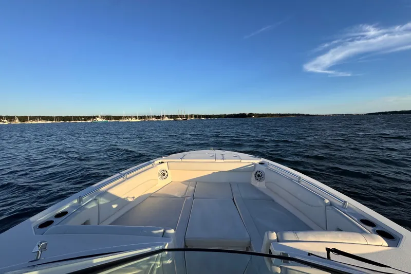 Slide: The Image of 2023 Cobia 330 Dual Console boat cruising on a calm, scenic lake. - 9