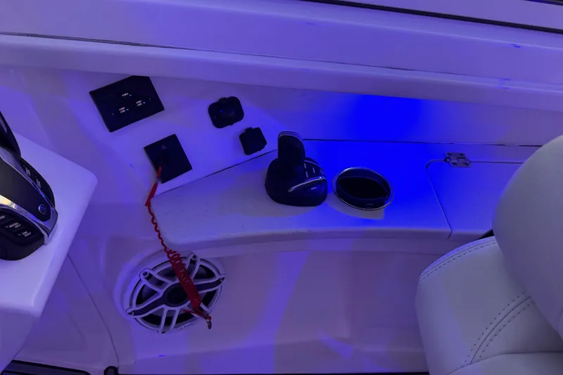 Slide: The Image of 2023 Cobia 330 Dual Console boat interior with controls and speaker, illuminated in blue light. - 12