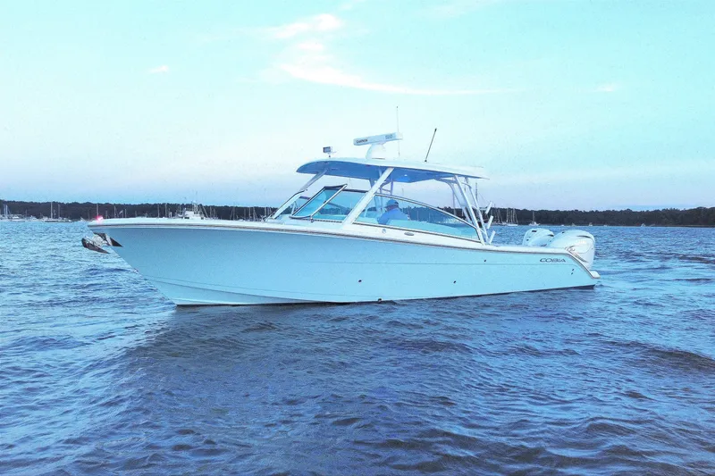 Slide: The Image of 2023 Cobia 330 Dual Console boat on calm water at sunset. - 6