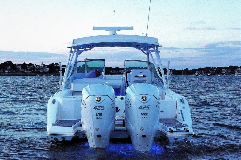 Slide: The Image of 2023 Cobia 330 Dual Console boat with twin 425 V8 engines on the water at dusk. - 1