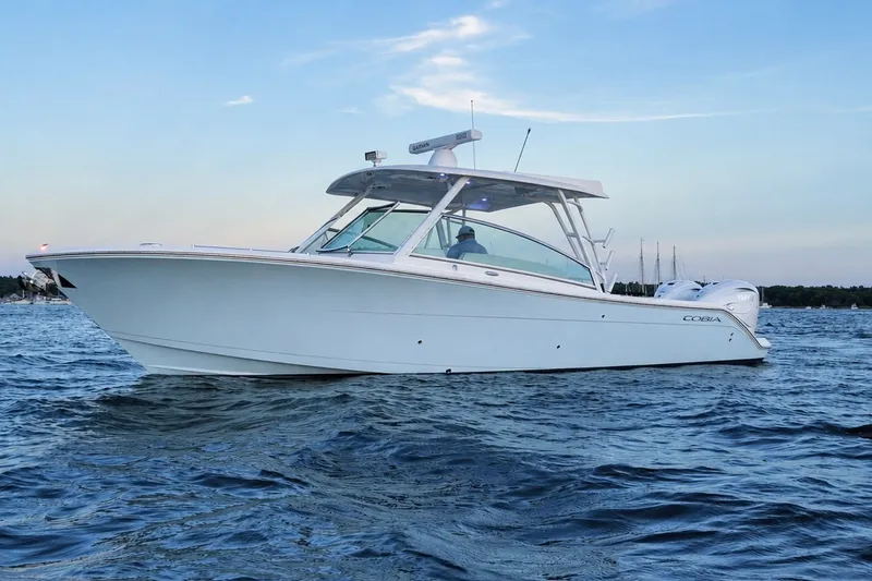 The Image of 2023 Cobia 330 Dual Console boat on open water at sunset. - 0