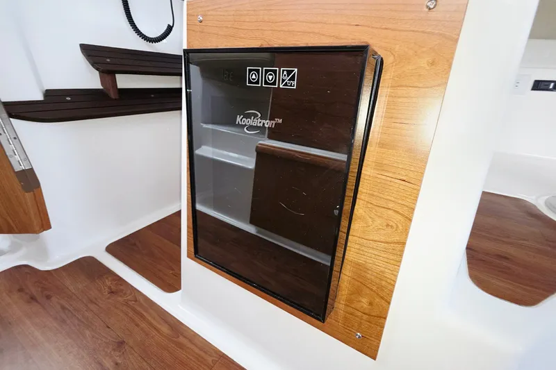 Slide: The Image of Interior of 2027 Cutwater C-32 Coupe featuring a Koolatron fridge with wood paneling. - 15