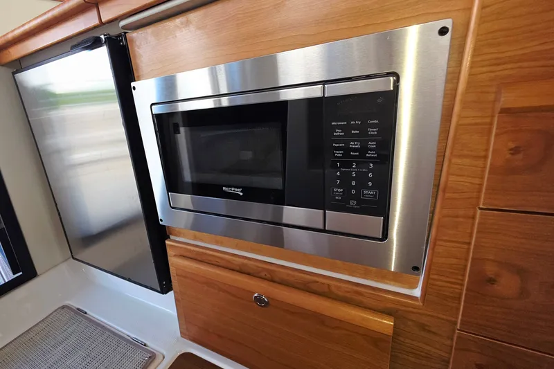 Slide: The Image of Built-in microwave in 2027 Cutwater C-32 Coupe kitchen with wooden cabinetry. - 14