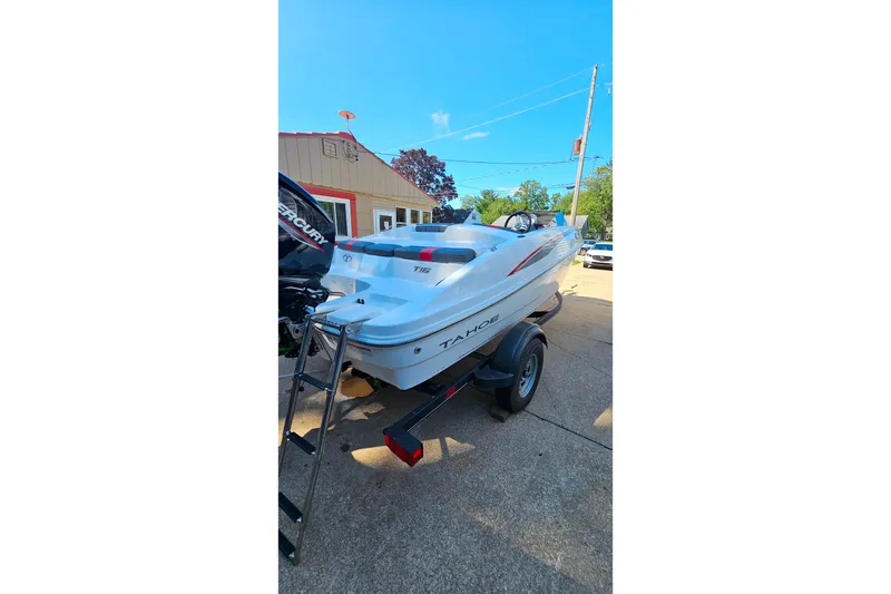 Slide: The Image of 2022 Tahoe T16 boat on trailer, parked outdoors under clear blue sky. - 3
