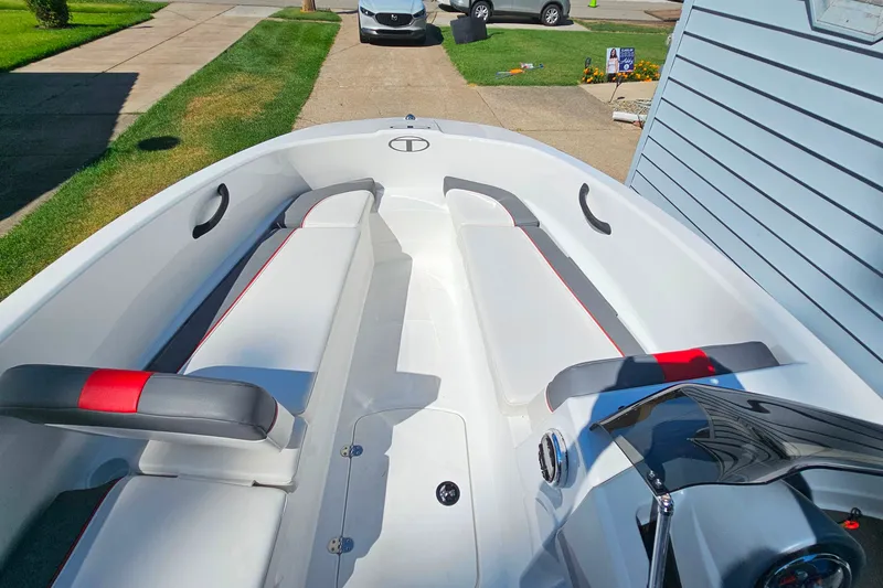 Slide: The Image of 2022 Tahoe T16 boat interior with white seating and red accents, parked in driveway. - 6