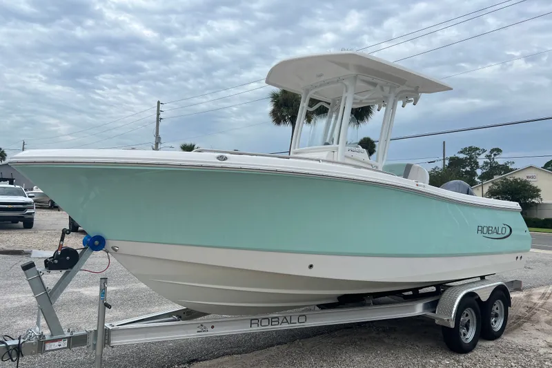 Slide: The Image of 2025 Robalo R230 Center Console boat on trailer, light blue hull, overcast sky. - 4