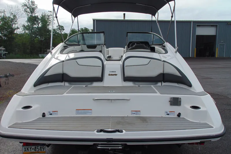 Slide: The Image of 2018 Yamaha Boats SX210, rear view, parked outdoors near a warehouse. - 8