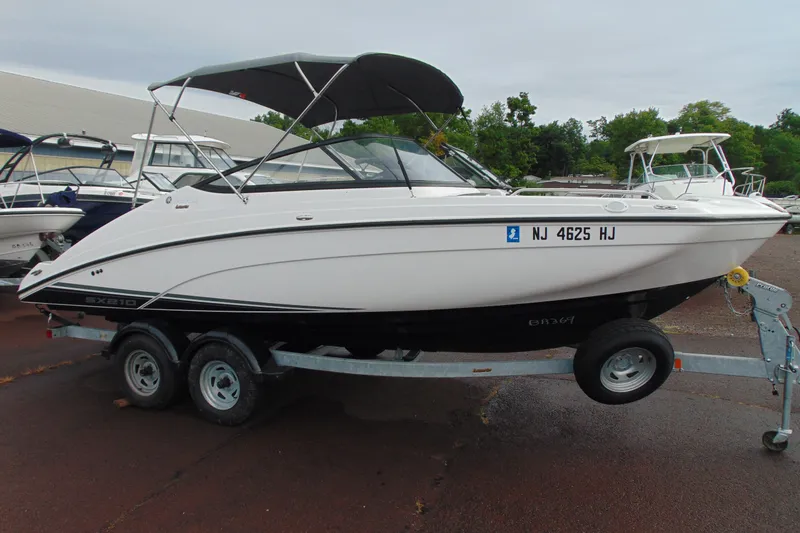 The Image of 2018 Yamaha Boats SX210 on trailer, parked outdoors with canopy and registration number visible. - 1