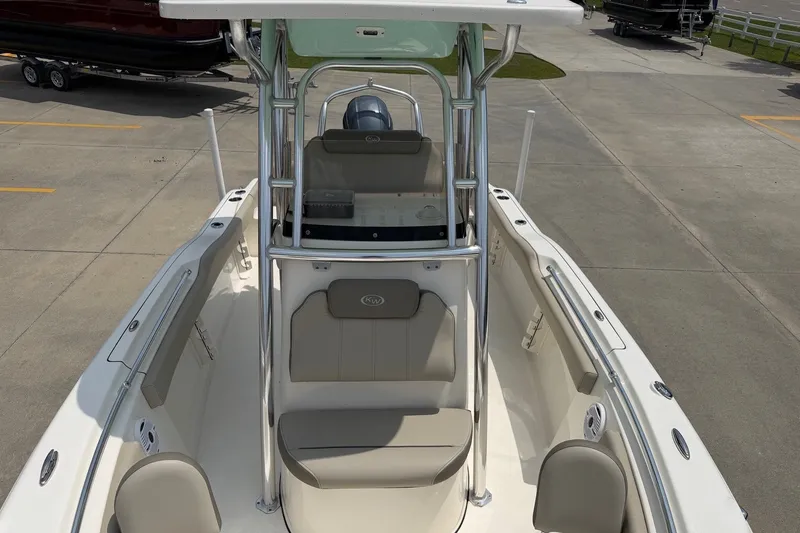 Slide: The Image of 2023 Key West 219 FS boat interior with seating and console, parked on concrete. - 17