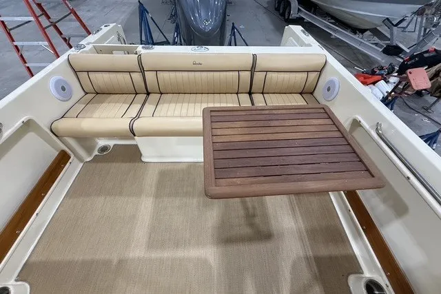 Slide: The Image of 2023 Rossiter 23 boat interior with beige seating and wooden table. - 10