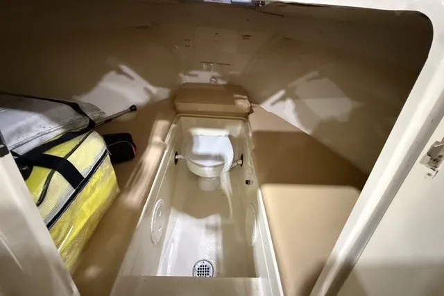 Slide: The Image of Interior of 2023 Rossiter 23 boat featuring compact marine toilet and storage area. - 18